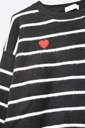 Maglione nero con dettaglio cuore rosso e strisce bianche.